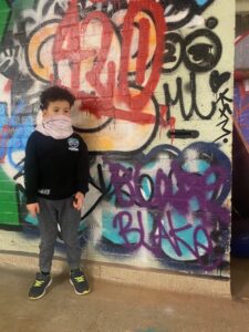 5 year old stands next to graffit